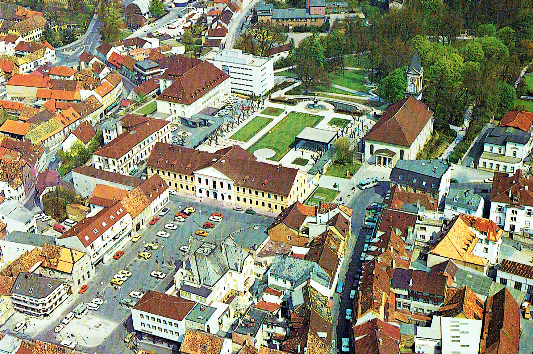 Abbildung 9: Luftbild von Schlossplatz und oberem Kurgarten mit Kurhaus, Kurmittelhaus, dem Kurparkhotel von 1937 und dem dahinter befindlichen Erweiterungsbau von 1972 noch mit Flachdach, welcher heute (2025) im Ansehen dem Hauptbau angeglichen worden ist. Im Hintergrund sieht man an der Stelle der heutigen Psychosomatischen Klinik die alte Turnhalle, die im August 1978 abgerissen wurde. Rechts der Ludwigskirche das elegante Hotel »Leininger Hof«, nach Abriss und grauslichem Neubau von 1979 heute das »Achat Hotel«. Die Kurgartenstraße ist noch keine Fußgängerzone. 1978.